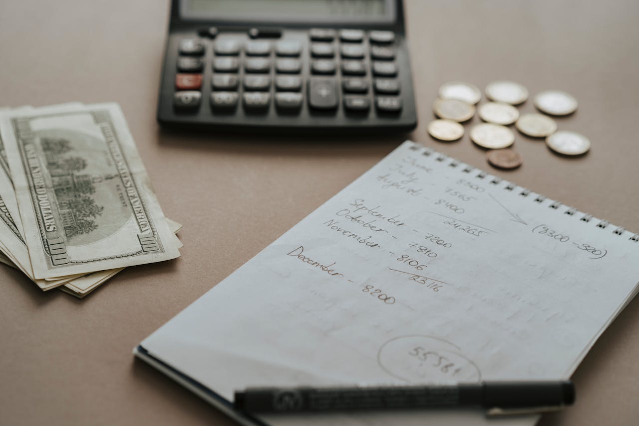 Desk setup showing calculator, cash, coins, and financial notes for budgeting.